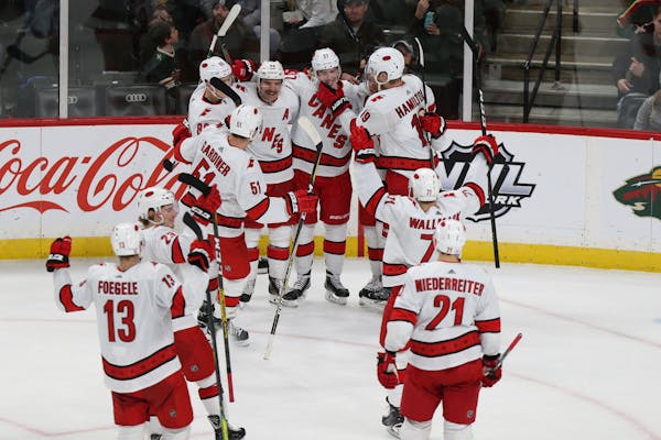 Carolina Hurricanes' Dougie Hamilton (19) grabs the chin of teammate Andrei Svechnikov (37) of Russia while the rest of the team joins to celebrate Sv