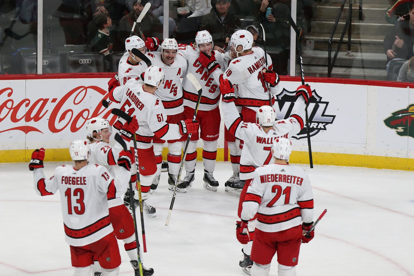 Carolina Hurricanes' Dougie Hamilton (19) grabs the chin of teammate Andrei Svechnikov (37) of Russia while the rest of the team joins to celebrate Svechnikov's game winning goal against the Minnesota Wild during overtime in an NHL hockey game Saturday, Nov. 16, 2019, in St. Paul, Minn. Carolina won 4-3 in overtime. (AP Photo/Stacy Bengs)