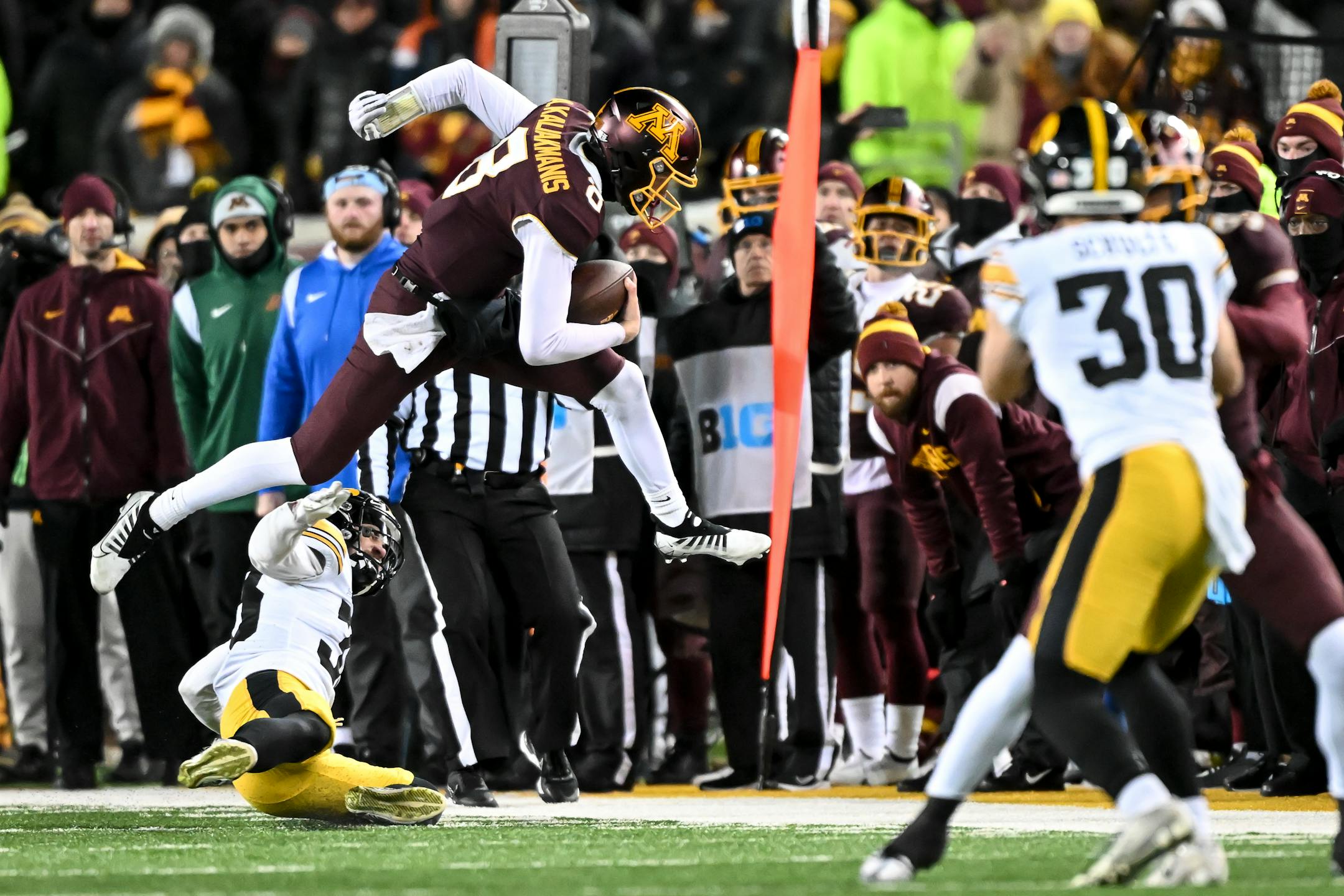 Minnesota Gophers quarterback Athan Kaliakmanis (8) leaps out of bounds during a run as he's hit by Iowa Hawkeyes defensive back Riley Moss (33) during the fourth quarter.