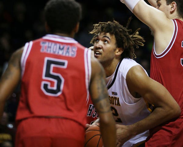 Gophers center Reggie Lynch (22) looked for an opening between Huskies Justin Thomas (5) and Marin Maric (34).