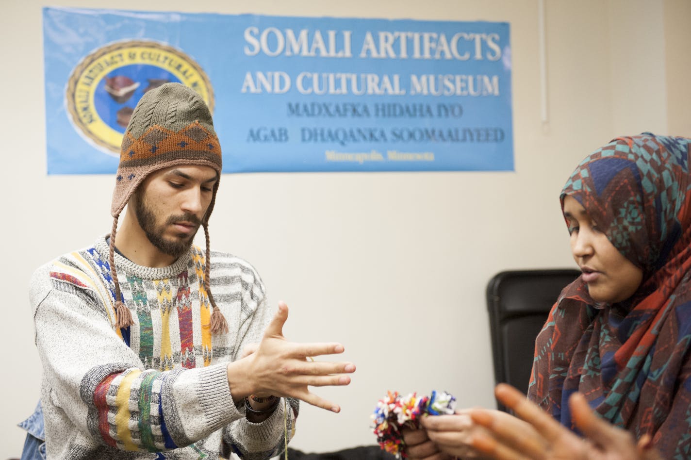 Nasra Noor teaches Jordan Hamilton (left) the traditional art of Somali weaving at the Somali Artifacts and Cultural Museum on East Lake Street. ] Photo by Leslie Plesser ORG XMIT: MIN1403281425130332