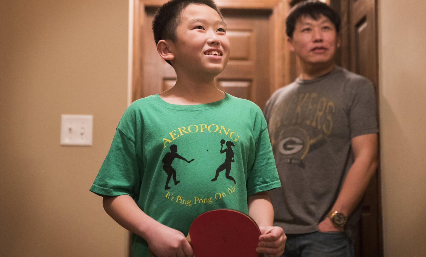 Kusa Xiong talks about Aeropong while his father Long Xiong stands behind him. ] LEILA NAVIDI &#xef; leila.navidi@startribune.com BACKGROUND INFORMATION: At home with the Xiong family in Brooklyn Park on Tuesday, January 9, 2018. Fifth grader Kusa Xiong wanted to find a way for his autistic sister to play and enjoy his favorite game: ping pong. Known as a kid inventor, Xiong ended up creating an entirely new, ping pong-style toy called Aeropong. His idea has captured national accolades in a cont