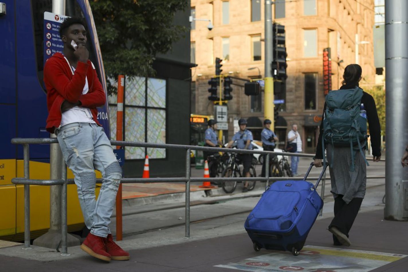 Myron White, left, waited for a Green Line train at 5th Street and Hennepin Avenue while Minneapolis police maintained a visible presence at the corner nearby. Three people have been shot in the area in two days, leading police to ramp up patrols.