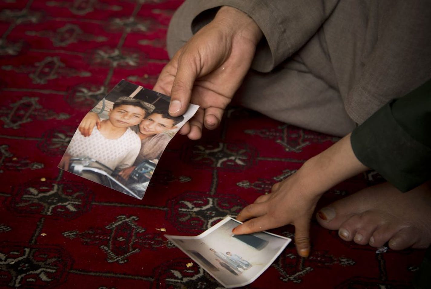 Mohammed Wazir, left, and his only surviving son, Habib Shahin show pictures or their slain relatives during an interview in Kandahar, Afghanistan on Monday, April 22, 2013. On March 11, 2012, a U.S. soldier burst into their home, and Wazir returned hours later to find 11 members of his family dead, their bodies partially burned. The youngest among the dead was his 1-year-old daughter Palawan Shah. U.S. Army Staff Sgt. Robert Bales of Lake Tapps, Washington, is accused of the killings. Bales has