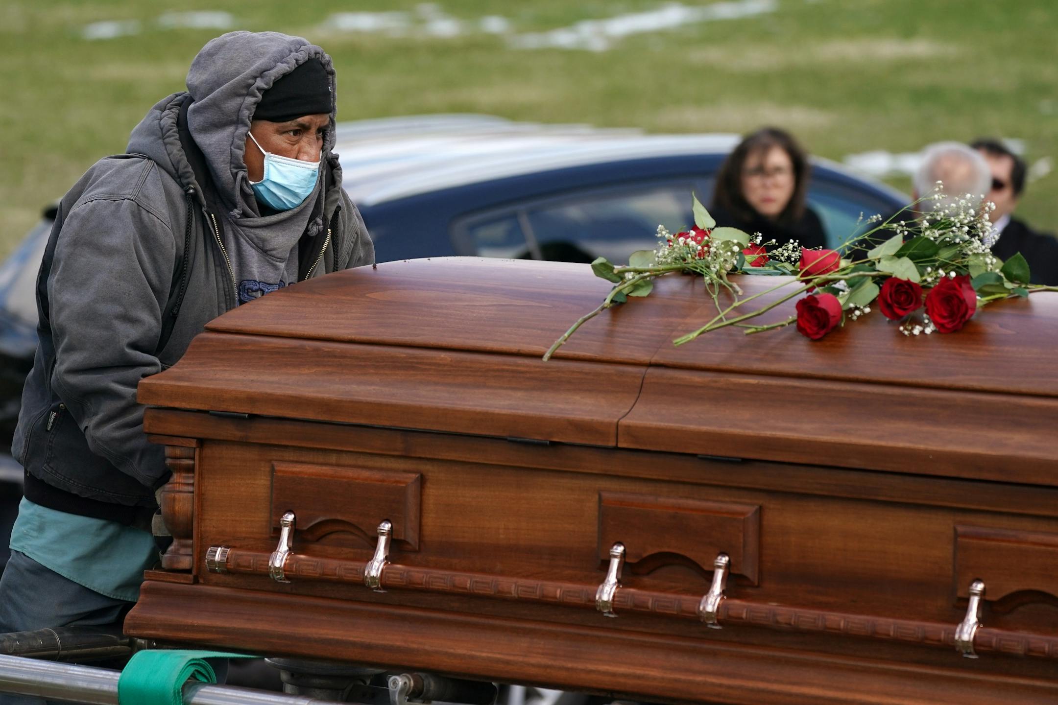 Cemetary workers wore masks as they lowered the casket of Elie Farhat, who recently died of COVID-19 at the age of 92, into his gravesite Thursday.