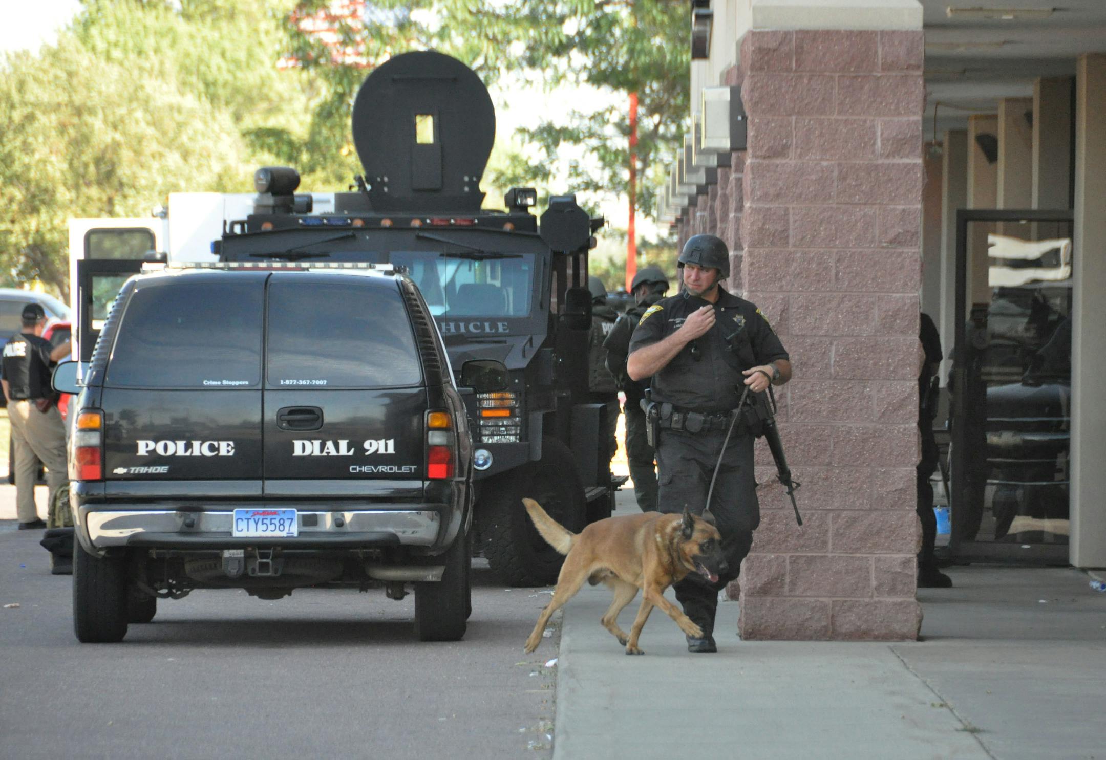 A Sioux Falls, S.D., SWAT team member walks a police dog out of a Cost Cutters hair salon, Tuesday, Sept. 11, 2012, after officers entered and found a gunman dead of an apparent self-inflicted gunshot wound. Police say the gunman kidnapped his two kids from a babysitter at gunpoint, shot an employee, Amanda Connors, to death in a car in the parking lot and then holed up inside the salon. (AP Photo/Dirk Lammers)