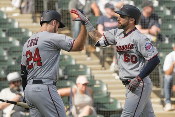 Minnesota Twins' C.J. Cron (24) congratulates Jake Cave (60) on his seventh-inning home run against the Chicago White Sox during a baseball game Thurs
