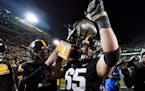 Iowa offensive lineman Tyler Linderbaum carries the Floyd of Rosedale trophy off the field after defeating the Gophers on, Saturday in Iowa City