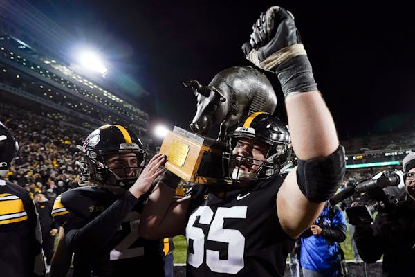 Iowa offensive lineman Tyler Linderbaum carries the Floyd of Rosedale trophy off the field after defeating the Gophers on, Saturday in Iowa City