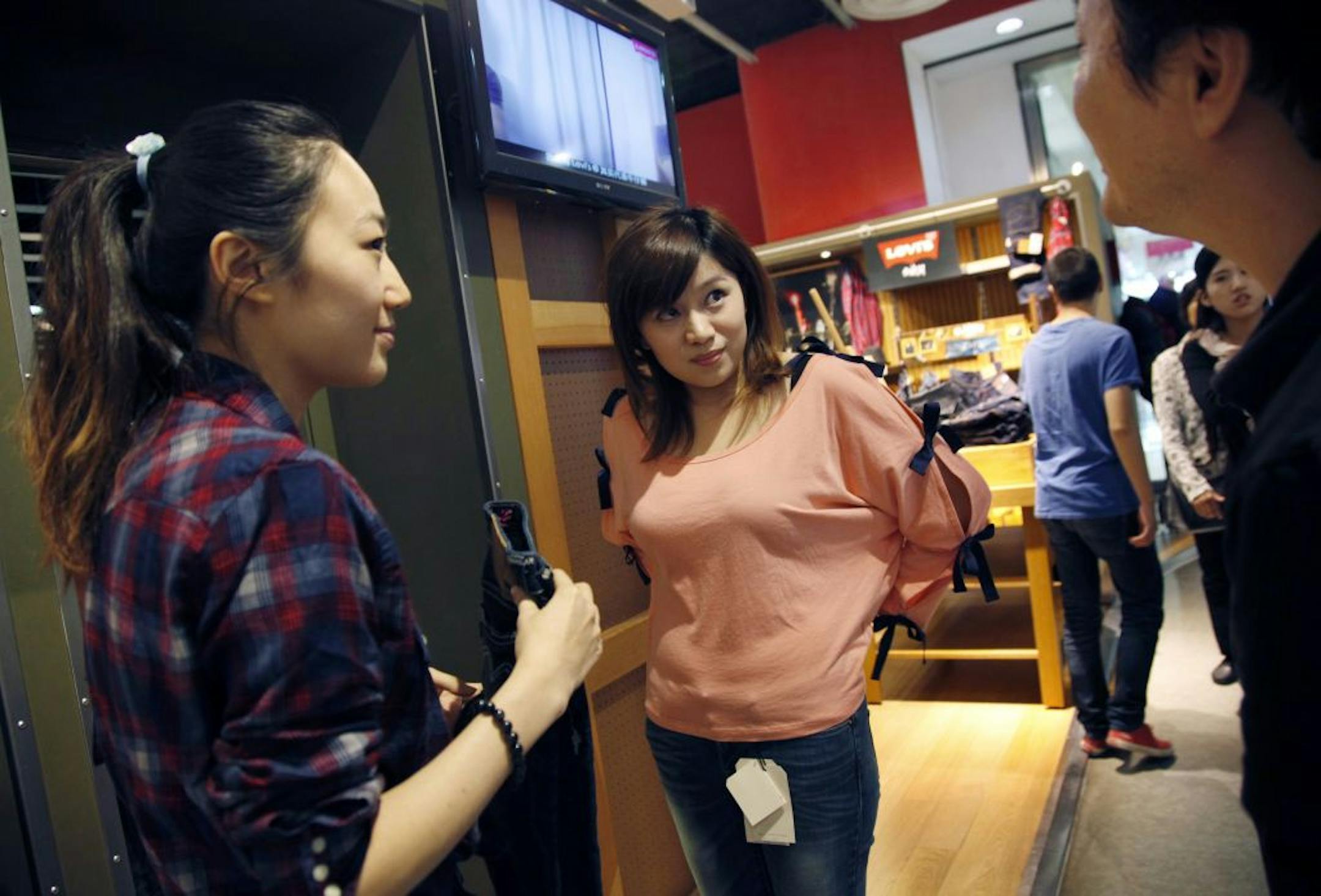 Amy He, center, models a pair of Levi's jeans for boyfirend Mike Dai and store employee Olivia Xu, left, at the Levi's outlet store at the Raffles City shopping mall in Shanghai, China, on September 22, 2011.