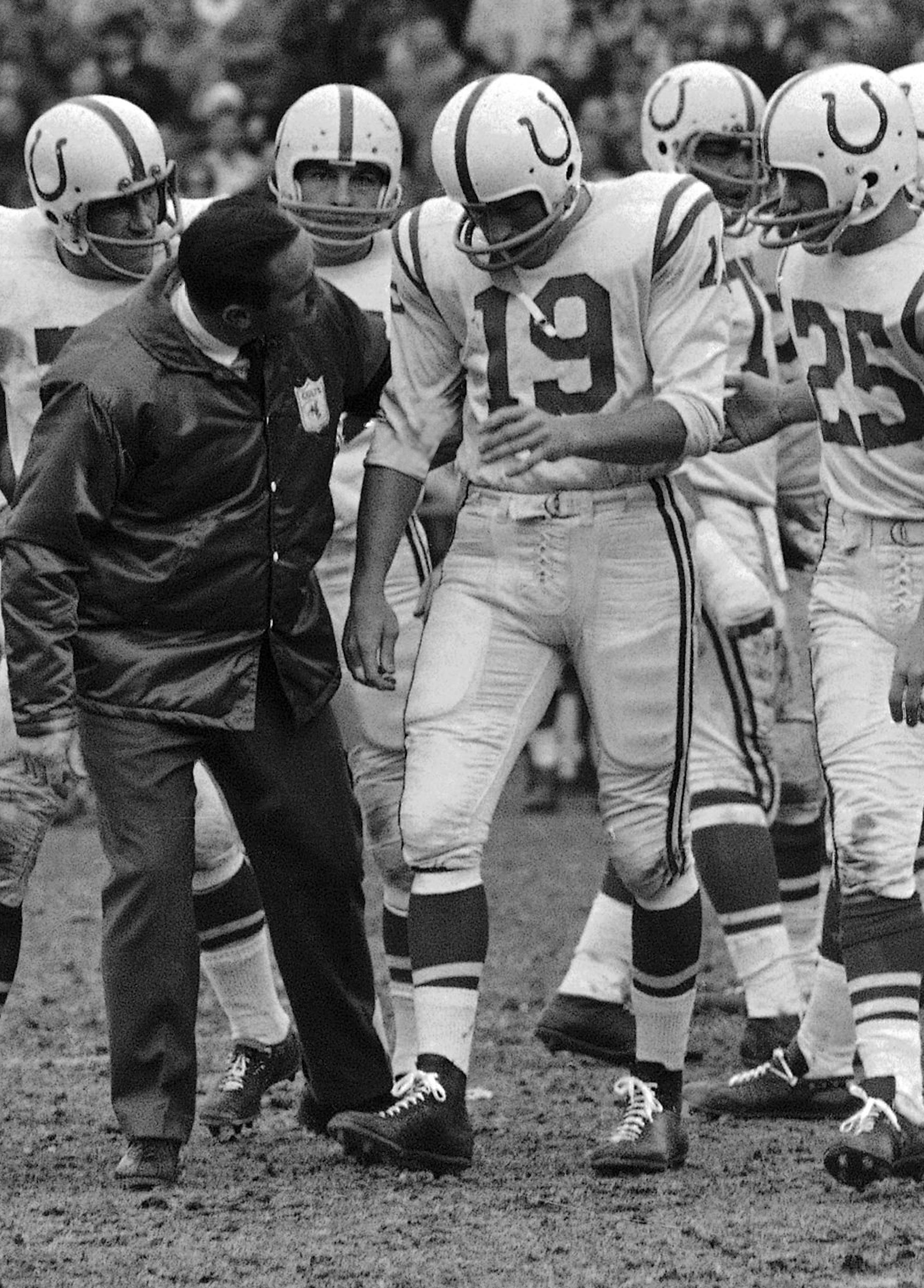 Quarterback Johnny Unitas of the Baltimore Colts limps to the sidelines, with the aid of Coach Don Shula, on his way in Baltimore on Dec. 5, 1965 to hospital for operation for torn ligaments in his knee. Unitas was hurt near the end of first half in a game won by the Chicago Bears 13-0. He will be out for the rest of the season. Steve Stonebreaker (31), Alex Hawkins (25), Raymond Berry (82). (AP Photo/JB) ORG XMIT: APHS272876