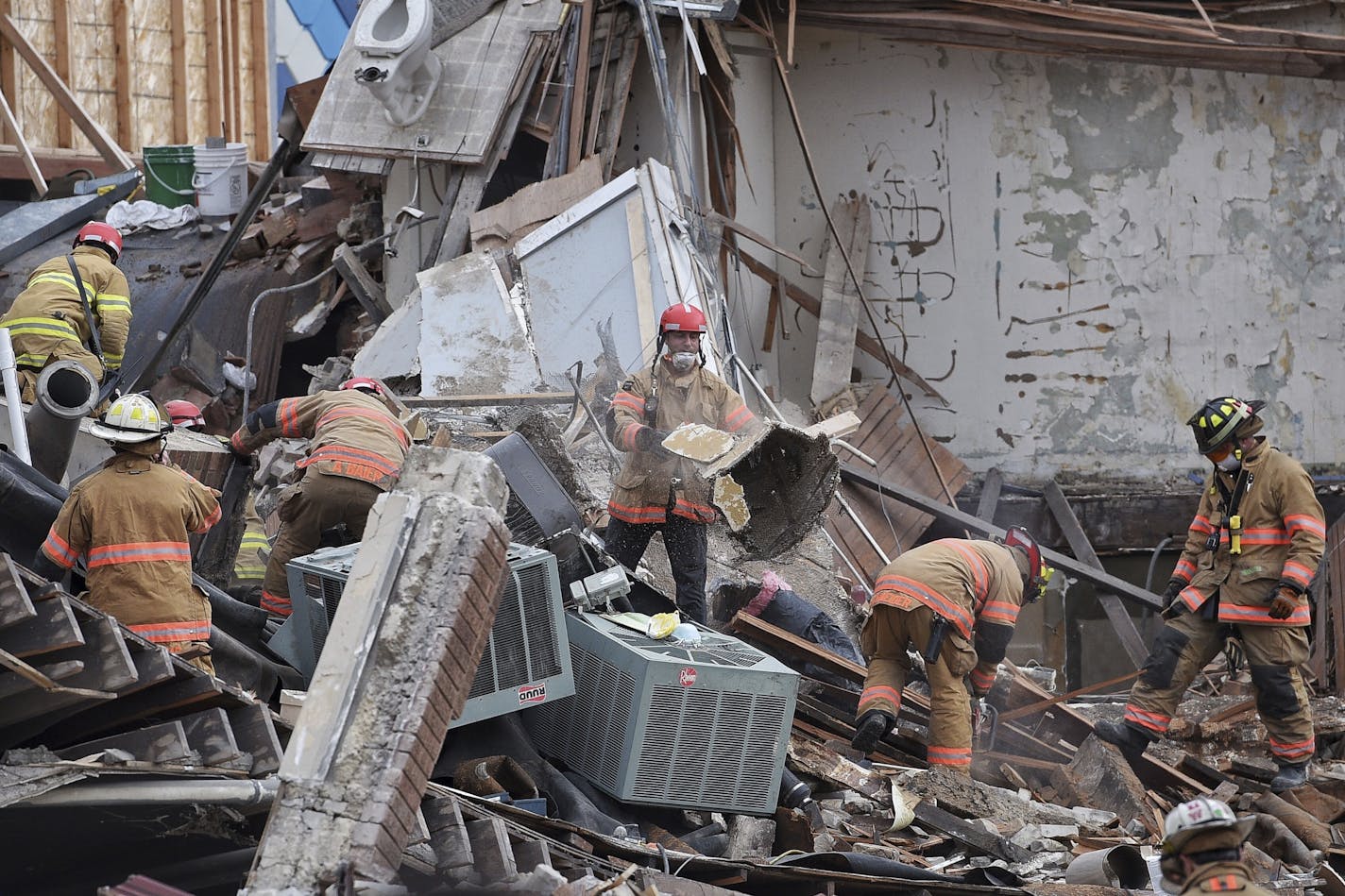 Emergency crews clear debris at the scene of building collapse in Sioux Falls, S.D., Friday, Dec. 2, 2016. A fire official says rescue workers are concerned about debris shifting as they try to free two people in the collapsed building.