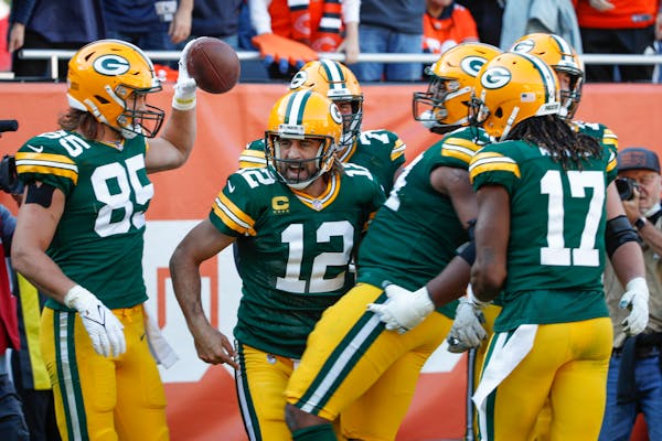 Green Bay Packers quarterback Aaron Rodgers (12) celebrates with teammates after scoring a touchdown during the second half of an NFL football game ag