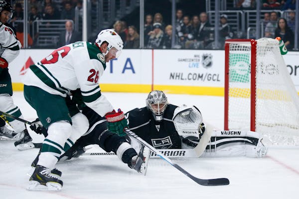 Minnesota Wild left wing Thomas Vanek, left, controls the puck in front of Los Angeles Kings goalie Jonathan Quick, right, during the first period of 