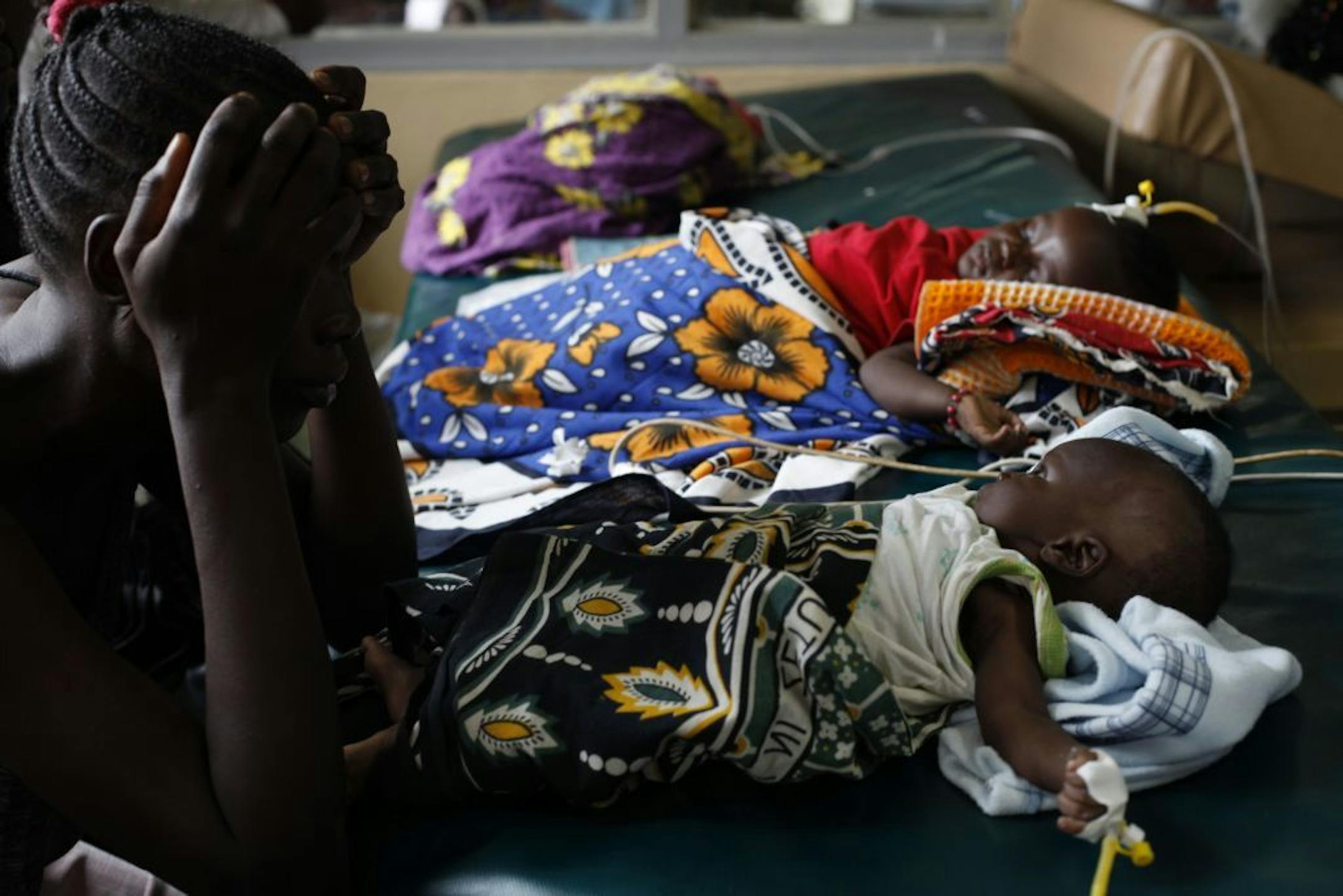 FILE - In this Friday, Oct. 30, 2009 file photo showing an unidetified mother as watches over her child who is suffering from severe malaria, as other children lay nearby, in the Siaya hospital in Western Kenya. Malaria is spread by mosquitoes and kills more than 650,000 people every year, mostly young children and pregnant women in Africa. GlaxoSmithKline and the PATH Malaria Vaccine Initiative, helped develop a new experimental malaria vaccine which was thought promising but is now turning out