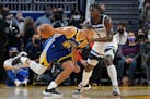 Warriors guard Stephen Curry, left, drives to the basket against Timberwolves forward Anthony Edwards during the first half Wednesday