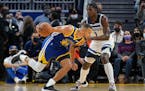 Warriors guard Stephen Curry, left, drives to the basket against Timberwolves forward Anthony Edwards during the first half Wednesday