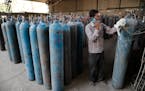A worker refilled medical oxygen cylinders at a charging station on the outskirts of Prayagraj, India, on Friday, April 23, 2021. India put oxygen tan