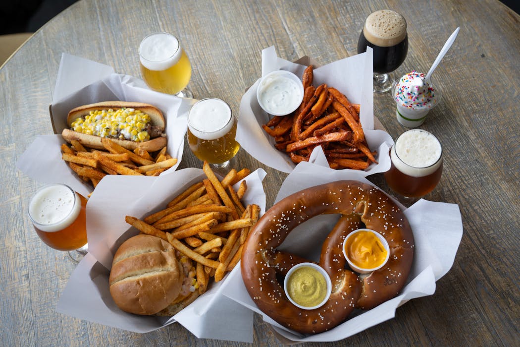 Menu items from Hodgepodge — from left, wild rice brat with beer-braised onions and sweet corn dill relish, the Sweet Corn Smashie, hot honey sweet potato fries with Top the Spud, a Bavarian soft pretzel and vanilla soft serve — all have beer pairings.