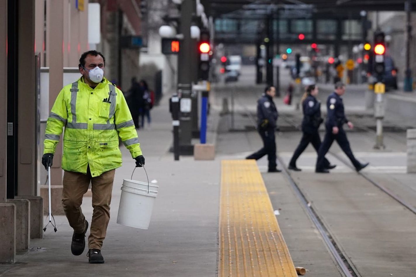 A worker wore a protective mask and gloves as he cleaned the light-rail platform outside Union Depot on Saturday in St. Paul.