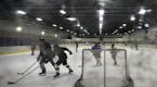 JIM GEHRZ &#x2022; jgehrz@startribune.comLights reflected off smudges left by hockey pucks on Plexiglas behind one goal at the Northeast Ice Center in