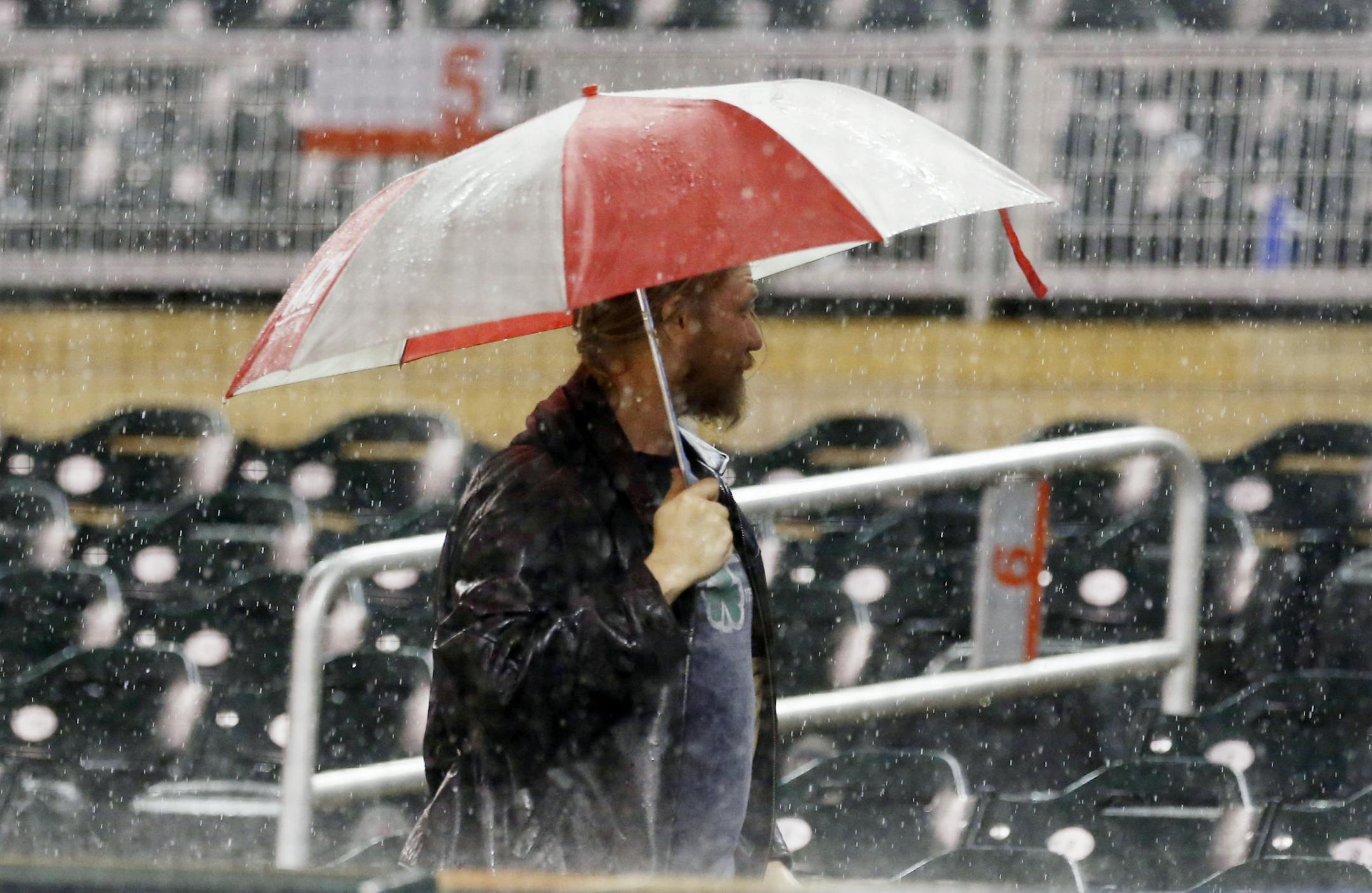 A baseball fan is protected by his umbrella after other fans cleared their seats when heavy rans forced a delay in the third inning of a baseball game between the Minnesota Twins and the Detroit Tigers on Wednesday, Sept. 21, 2016, in Minneapolis.