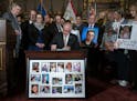 Gov. Tim Walz signed the hands-free cellphone bill into law while surrounded by family members of victims of distracted driving at the Capitol in St. 