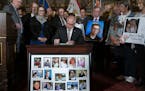 Gov. Tim Walz signed the hands-free cellphone bill into law while surrounded by family members of victims of distracted driving at the Capitol in St. 