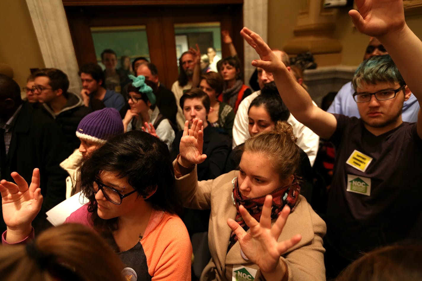 People in the crowd raised their hands in support of a resident speaking out about the lack of funding for racial equality during a packed meeting on the budget in the city council chambers at City Hall in Minneapolis, Minn. on Wednesday, December 10, 2014.