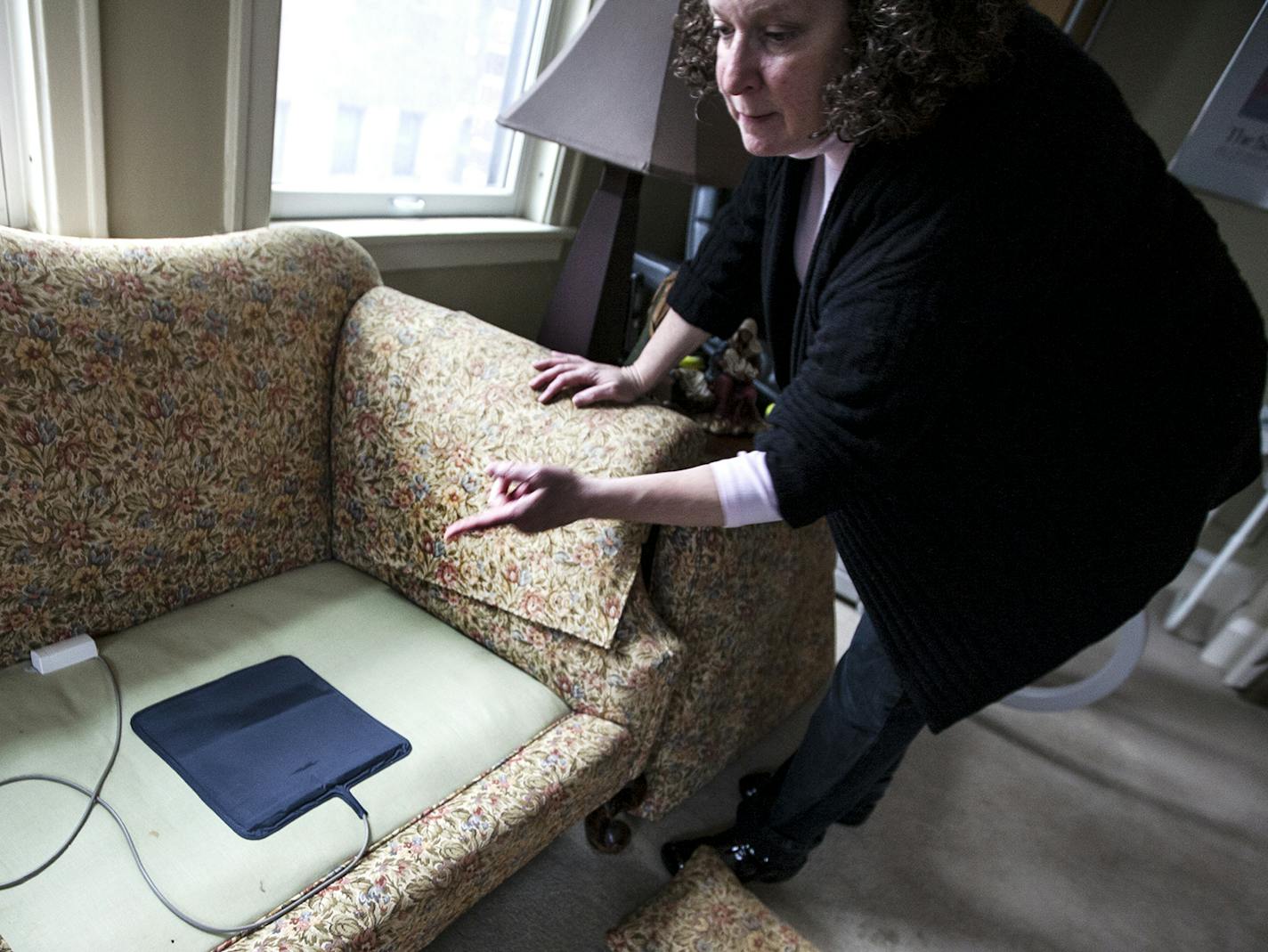 Sally Evans points out the motion sensors in place under couch cushions at the condo she shares with her mother Wilma Evans in St. Paul December 15, 2015. Wilma has dementia, and when there is movement sensed, a recorded message rings to Sally's phone. (Courtney Perry/Special to the Star Tribune)