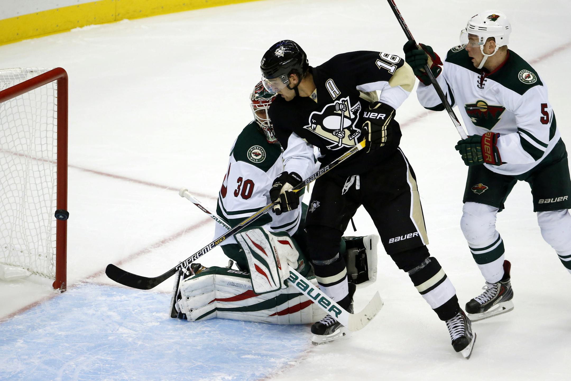 Pittsburgh Penguins' Brandon Sutter (16) backhands the game-winning goal in overtime behind Minnesota Wild goalie Ilya Bryzgalov (30) and defenseman Christian Folin (5) during an NHL preseason hockey game in Pittsburgh Thursday, Sept. 25, 2014. The Penguins won 3-2. (AP Photo/Gene J. Puskar)