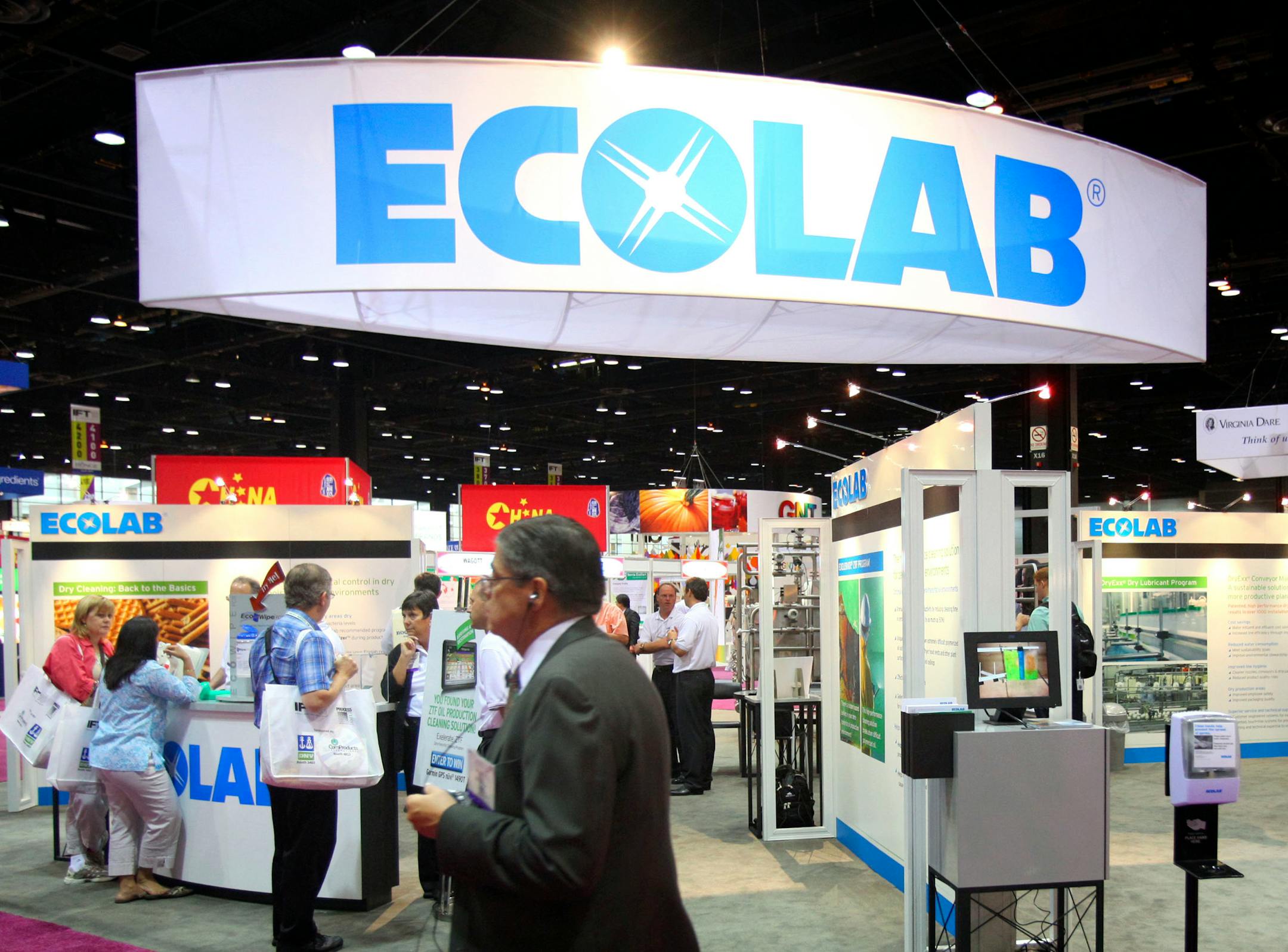 Attendees walk past the Ecolab Inc. booth at the Institute of Food Technologists Annual Meeting & Food Expo In Chicago, Illinois, U.S., on Monday, July 19, 2010. The meeting brings together professionals from the science and business sectors of the food industry to learn about the newest trends and products. Photographer: Tim Boyle/Bloomberg