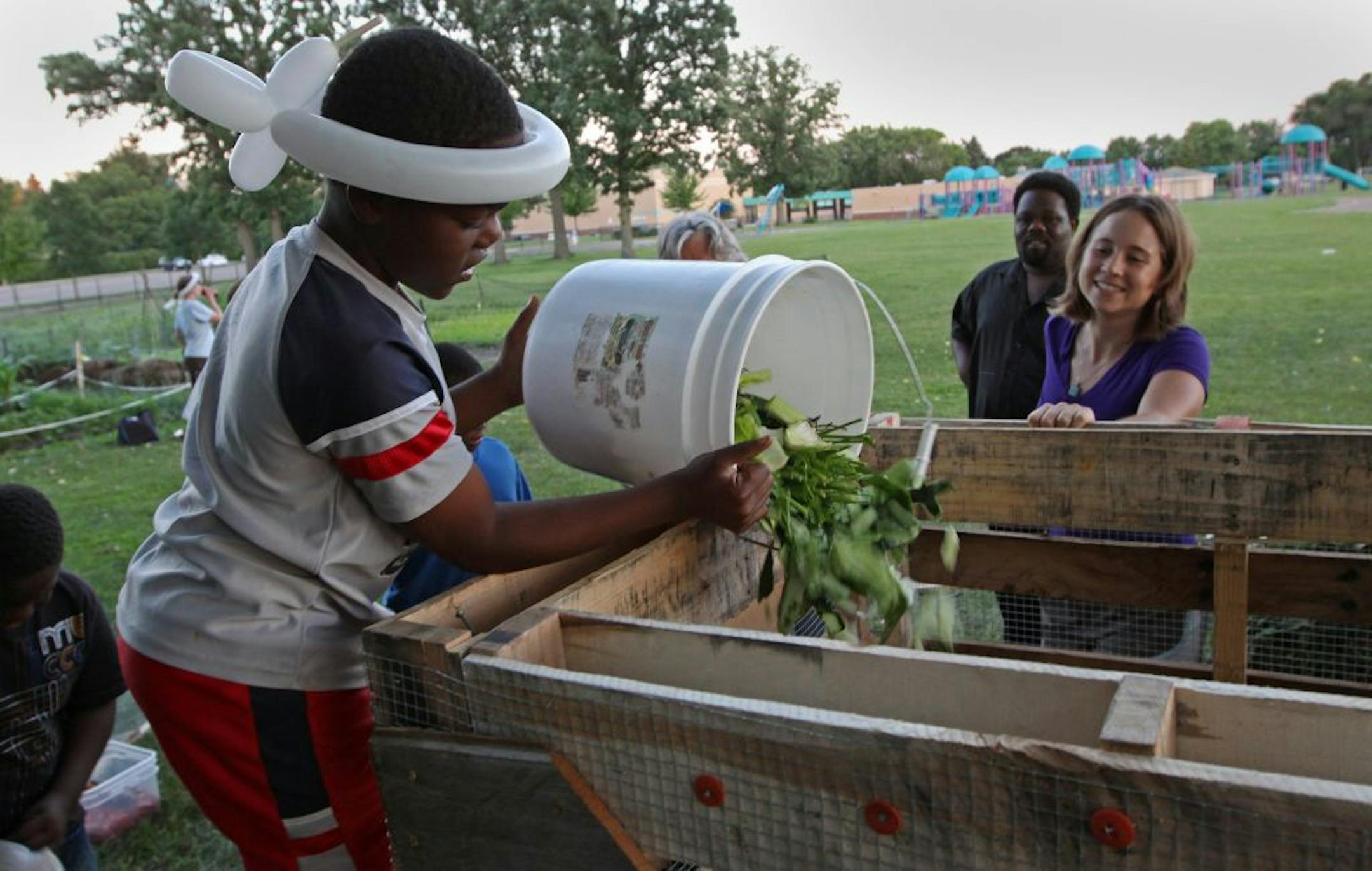 Volunteer Ryan Thomas poured compost material into the finished compost bin as Rebecca Harnik of the Compostadores, a group of people committed to "keeping nutrients in the neighborhood" by building compost bins, watched. The volunteer group was building a compost bin at the Edgerton Community Garden in St. Paul.