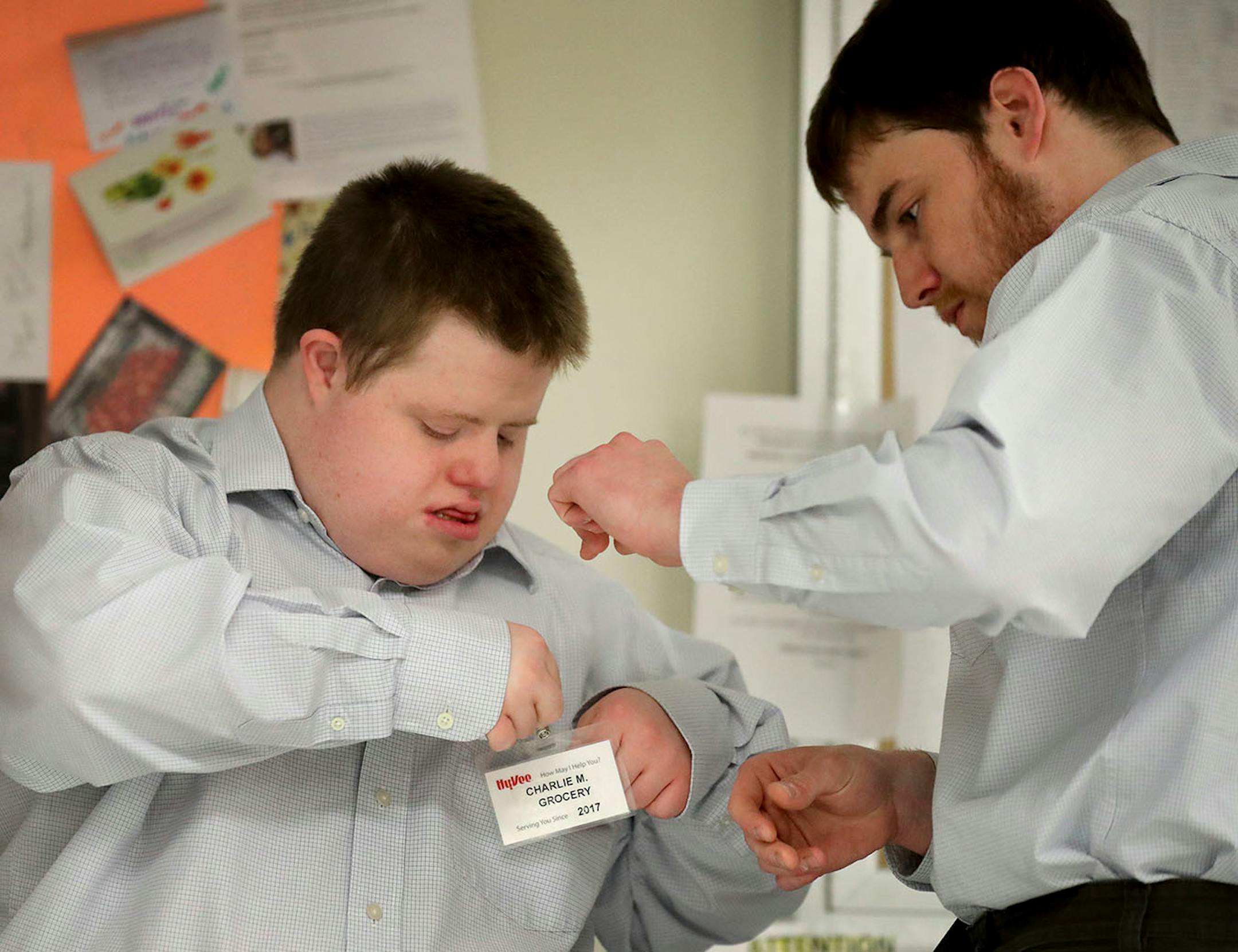 A year ago, Charlie McGrory, who has Down syndrome, was miserable. He was spending most of his days at a segregated sheltered workshop in Winona, where he was not even making minimum age. Now, thanks to an ambitous job outreach program, McGrory is working at a Hy-Vee store in Winona for $11 an hour, and has gained new confidence. Here, after arriving at his job as a bagger at Hy-Vee Charlie get s help from his brother Andy, who is also his job coach, putting on his name tag Tuesday, May 1, 2018,