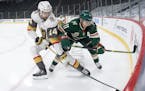 Nicolas Hague (14) of the Las Vegas Golden Knights and Zach Parise (11) of the Minnesota Wild fought for the puck in the first period.