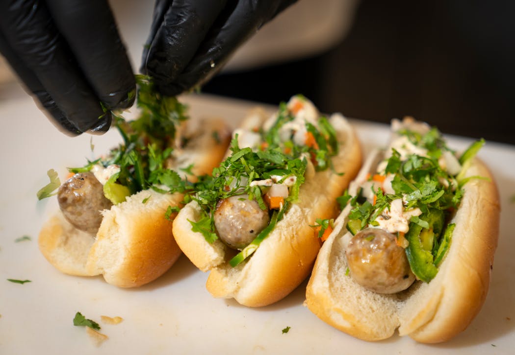 Union Hmong Kitchen Banh Mi Brats are prepped for guests during a tour of the new food for 2024 at Target Field in Minneapolis on Monday.