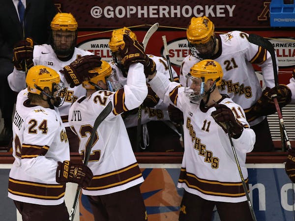 Gophers Travis Boyd, left, and Sam Warning celebrated with teammates after the play had been viewed as a goal Boyd's second goal during the first peri