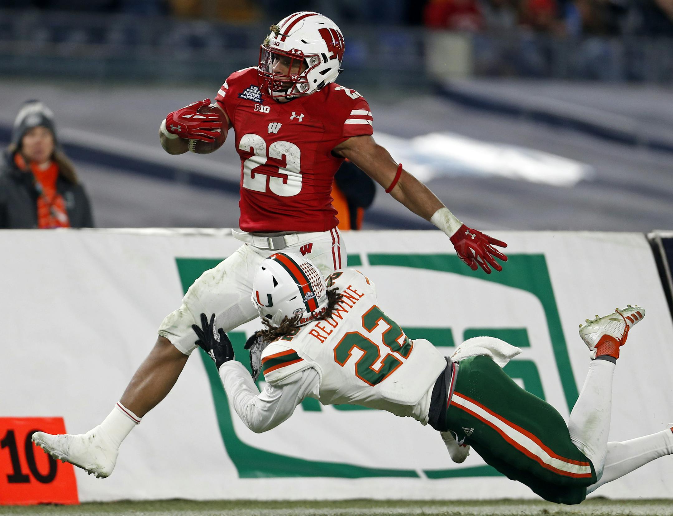 Wisconsin running back Jonathan Taylor (23) is tackled by Miami defensive back Sheldrick Redwine (22) during the second half of the Pinstripe Bowl NCAA college football game Thursday, Dec. 27, 2018, in New York. Wisconsin defeated Miami 35-3. (AP Photo/Adam Hunger)