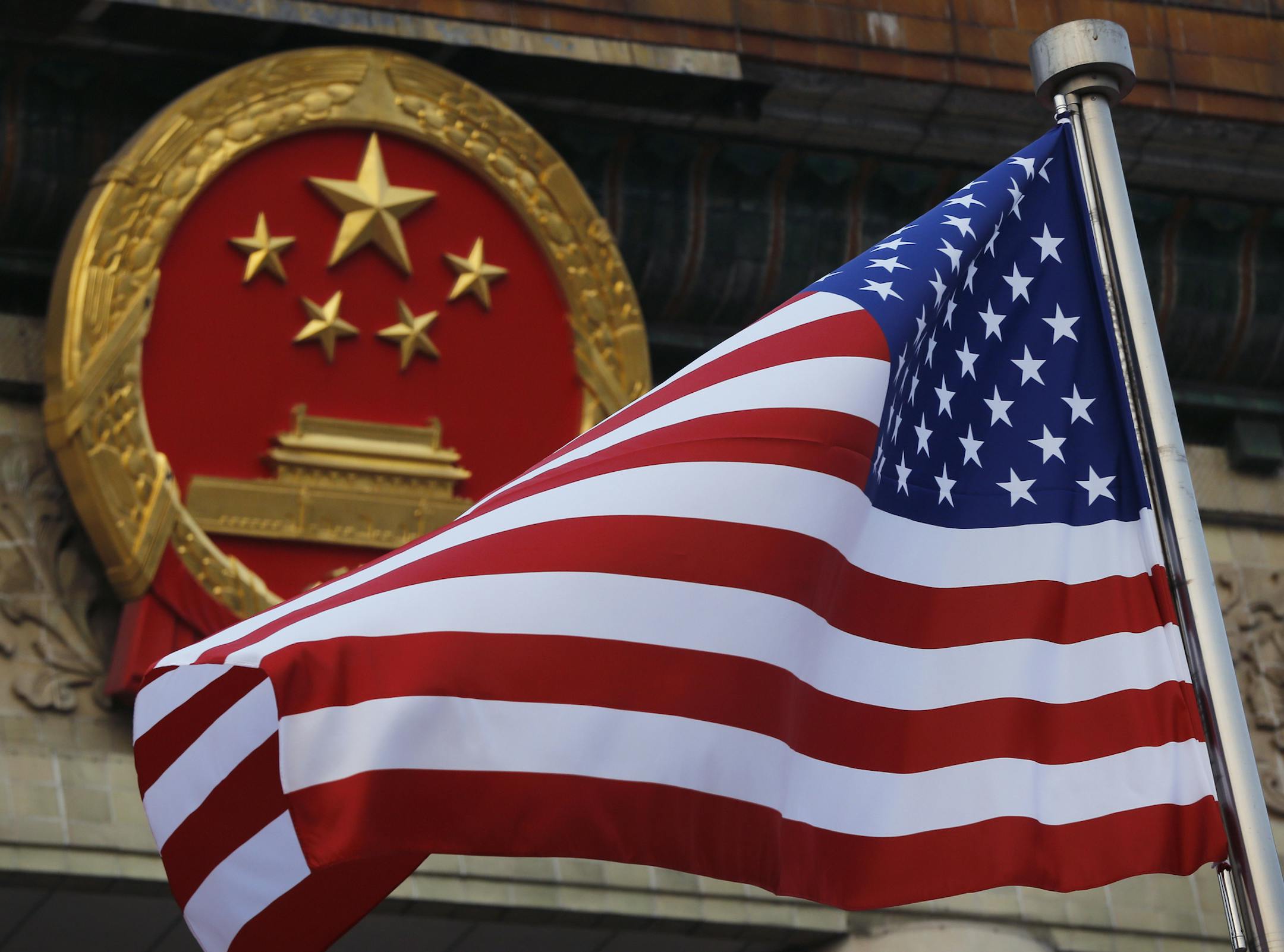 FILE - In this Nov. 9, 2017, file photo, an American flag is flown next to the Chinese national emblem during a welcome ceremony for visiting U.S. China says accusations against an alleged spy of attempting to steal trade secrets from several American aviation and aerospace companies were "made out of thin air." (AP Photo/Andy Wong, File)