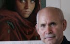 FILE -- Photographer Steve McCurry poses for a portrait in New York in September 2008 with a poster of his iconic photo of the Afghan girl, Sharbat Gu