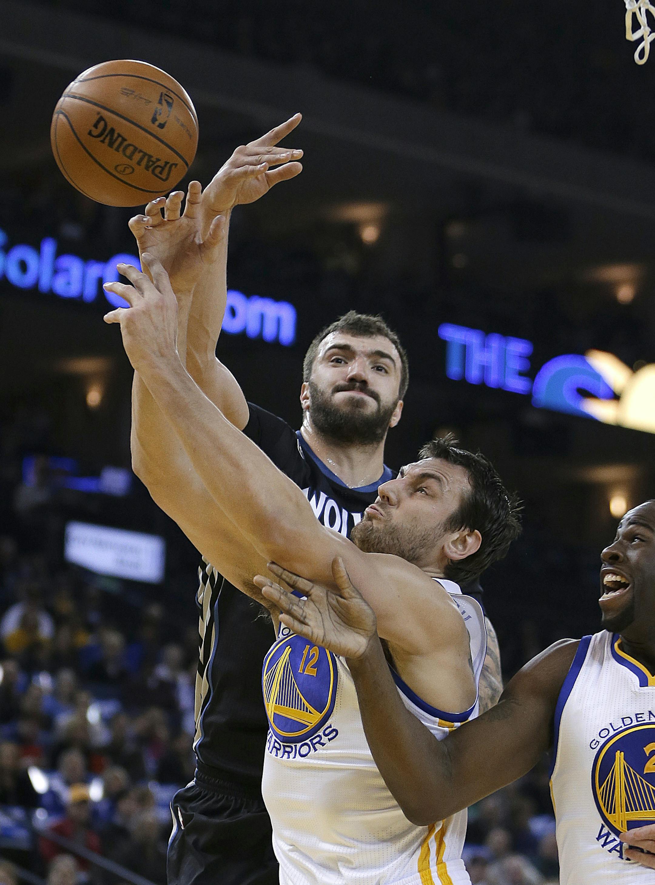 Minnesota Timberwolves' Nikola Pekovic, left, and Golden State Warriors' Andrew Bogut (12) reach for a rebound during the first half of an NBA basketball game Friday, Jan. 24, 2014, in Oakland, Calif. At right is Warriors' Draymond Green (23). (AP Photo/Ben Margot)