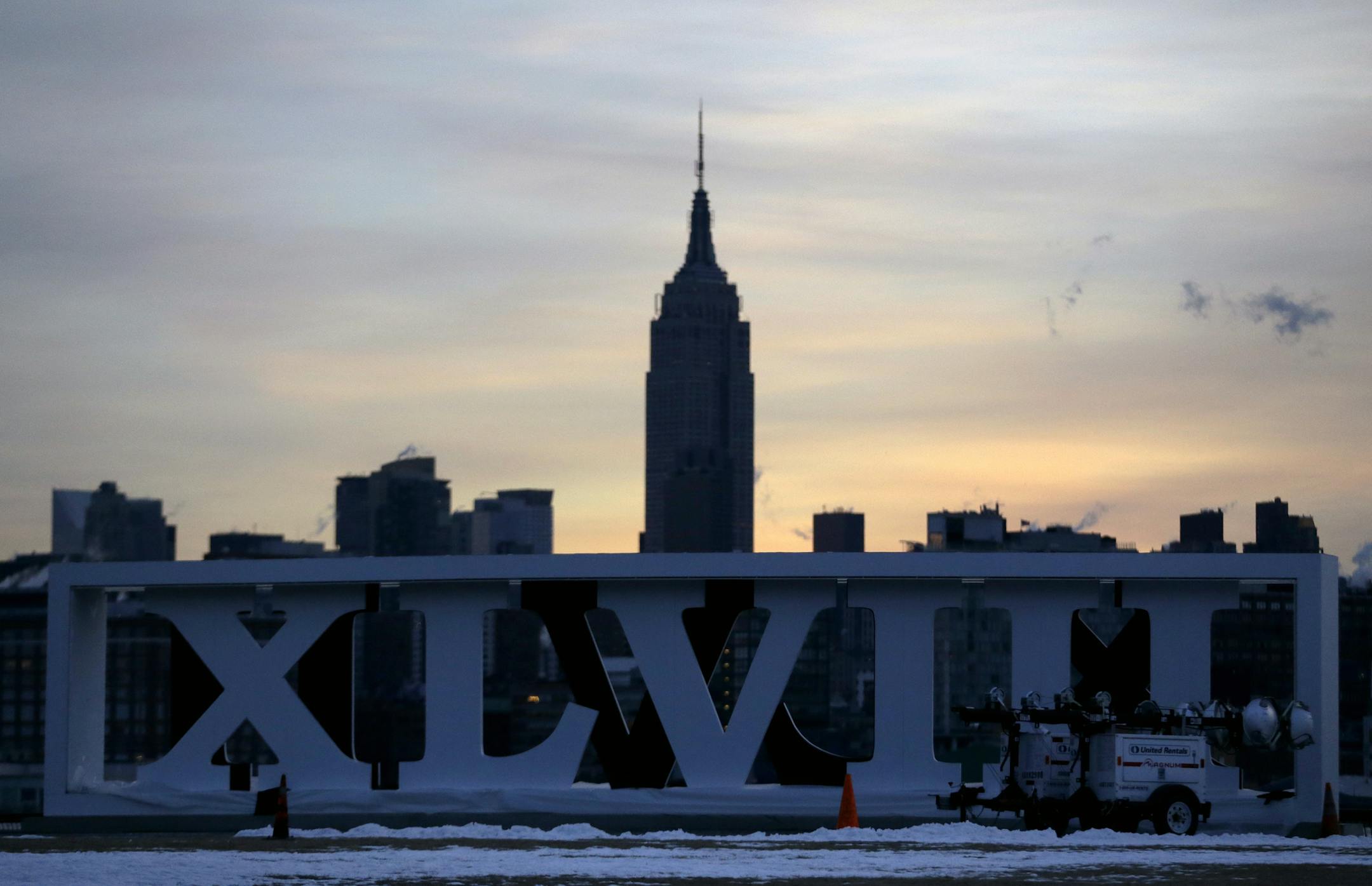 The Empire State Building, top, backdrops Roman numerals for the NFL Super Bowl XLVIII football game standing during sunrise at Pier A Park in Hoboken, N.J., Tuesday, Jan. 28, 2014. The Seattle Seahawks and the Denver Broncos are scheduled to play on Sunday, Feb. 2, 2014, at MetLife Stadium in East Rutherford, N.J. (AP Photo/Julio Cortez)