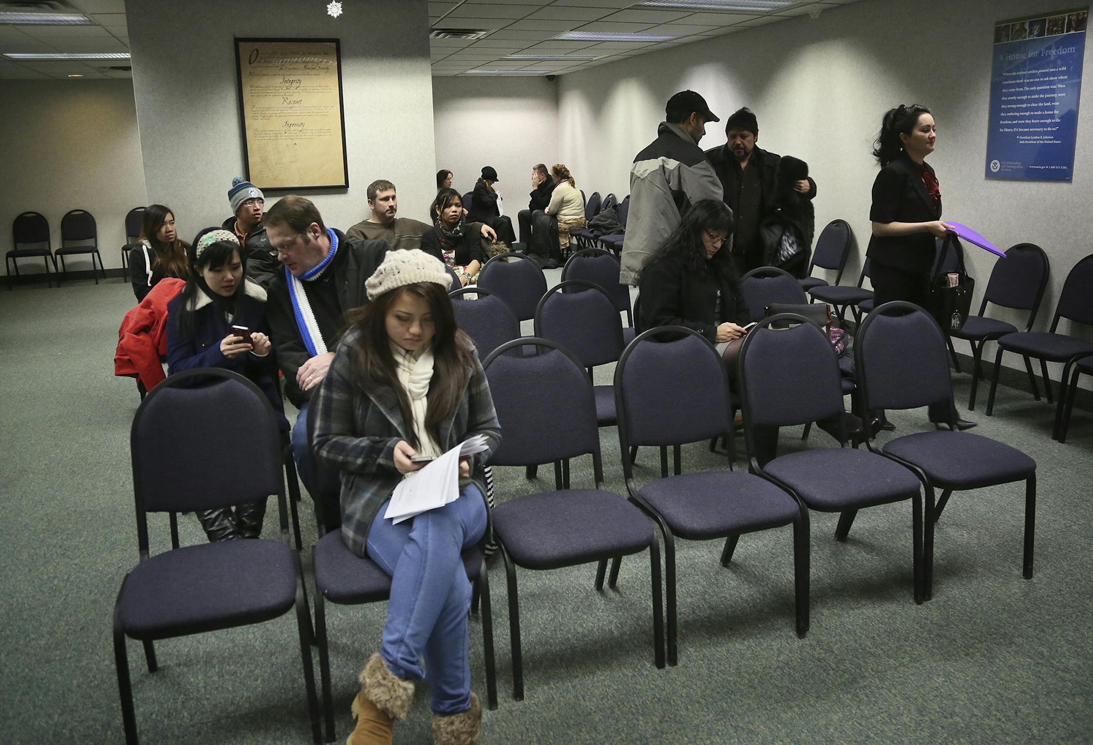 Immigrants, along with spouses or friends, sit in a waiting room at the US Customs and Immigration Services offices Thursday, Feb. 6, 2014, in Bloomington.