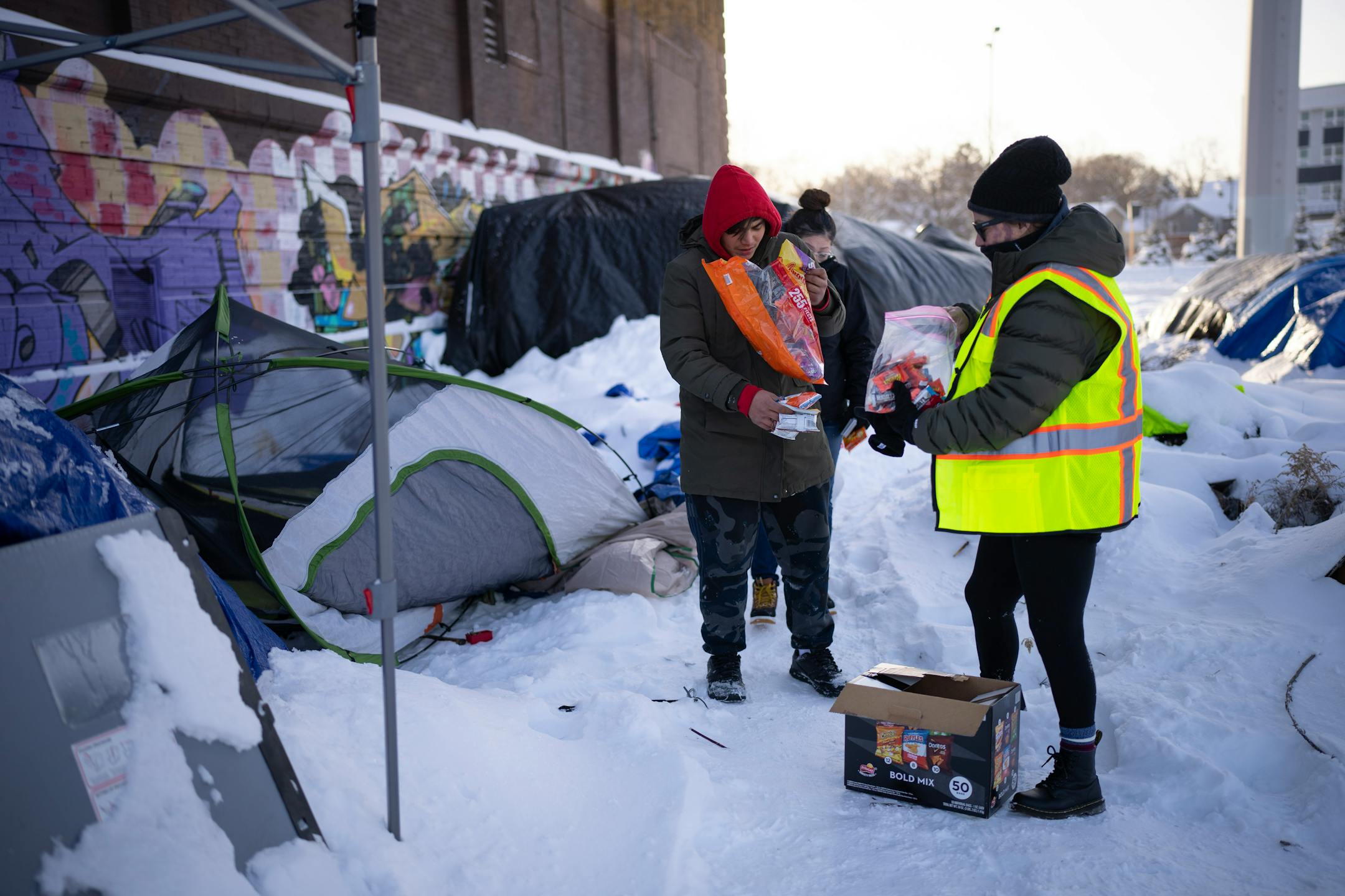 Outreach worker Leah Skjefte gave snacks to a young man living in an encampment along Hiawatha Ave. as she and Dava Beaulieu checked on their well being and offered hand warmers and snacks Thursday afternoon. Homeless outreach workers for the American Indian Community Development Corp. (AICDC), checked several homeless encampments to offer hand warmers and snacks or a ride to a shelter on a dangerously cold afternoon in Minneapolis Thursday, December 22, 2022.