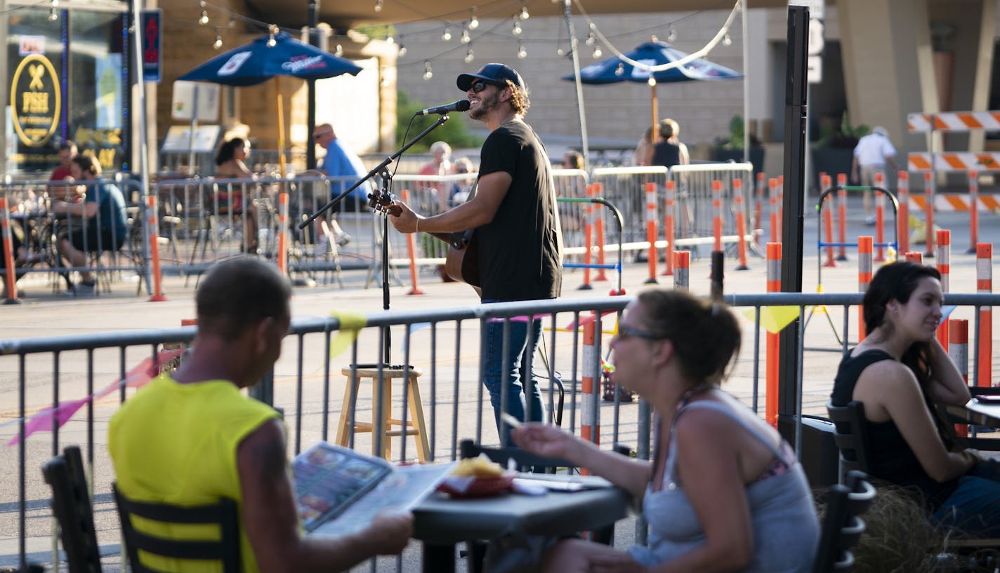 Musician Matt Browne, hired by Spiral Brewery, performed on a closed downtown street in Hastings, where about 10 restaurants feature patio dining.