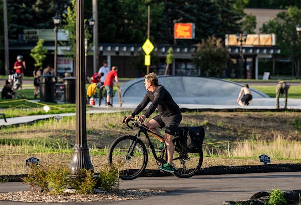 A biker watches skaters enjoy Gateway Park after temperatures dip in the early evening in St. Paul, Minn., on Tuesday, June 14, 2022. After years of p