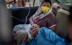 A patient breathes with the help of oxygen provided by a Gurdwara, Sikh place of worship, inside a car in New Delhi, India, Saturday, April 24, 2021. 