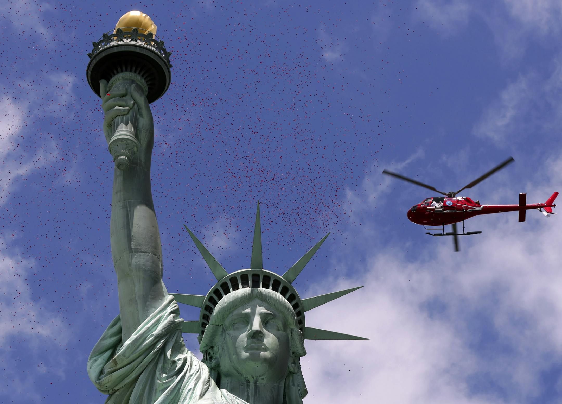 One of three helicopters showered 1-million rose petals on the Statue of Liberty during a ceremony commemorating the 70th anniversary of the D-Day invasion, on Liberty Island in New York Harbor, Friday, June 6, 2014. (AP Photo/Richard Drew)