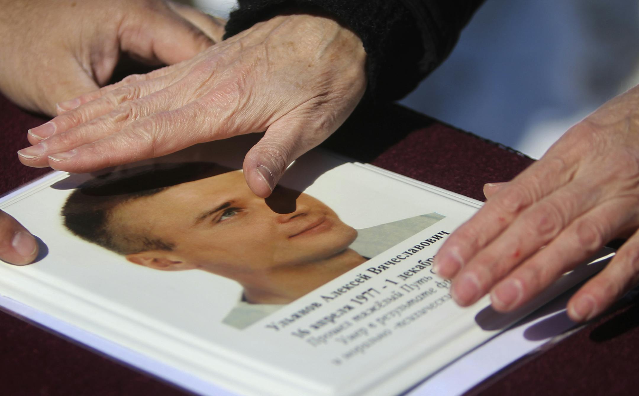 Russian immigrant Tamara Oulanova of Minneapolis spent $13,000 and 10 years to exhume her son's body from a Russian grave and bring him here in the U.S. in order to be close to him. Here, Oulanova, 56, touched a photo of her son Alexey that she had taped to the top of his casket before he was buried Tuesday, March 19, 2013, in St. Mary's Orthodox Cathedral Cemetery in St. Anthony, MN. Alexey, 26, had been beaten by thugs back in Russian in 2000, and died of his injuries in 2003.] (DAVID JOLES/ST