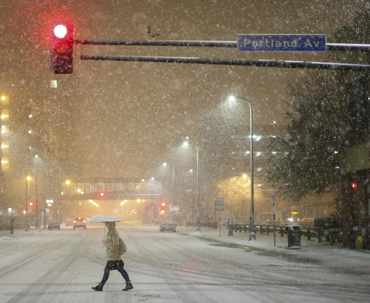 A pedestrian crossed 3rd St. S. as heavy snow fell early Monday night.